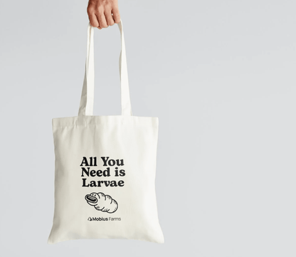 Tote bag with 'All You Need is Larvae' text and Mobius Farms logo on a light gray background