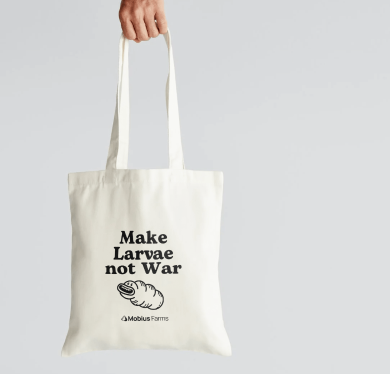 Tote bag with 'Make Larvae not War' text and Mobius Farms logo on a light gray background
