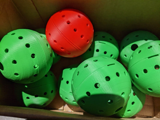 Red and Green Plastic 3d printed Chicken Treat Balls with small holes for treats to fall out